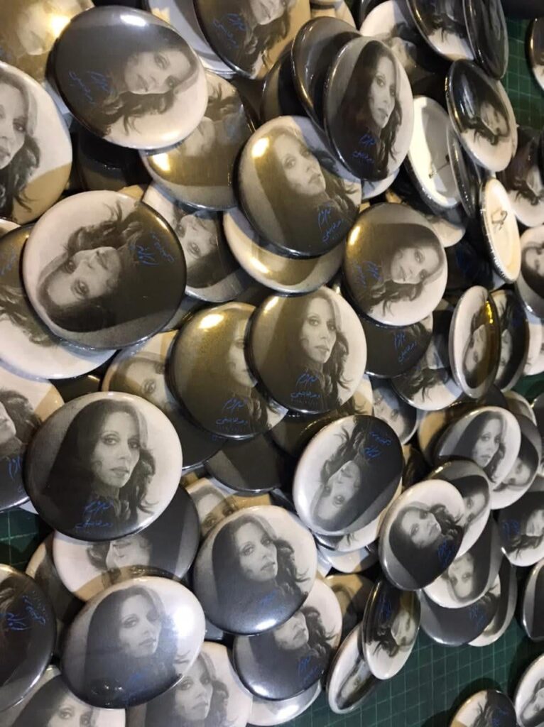 Round pin badges featuring monochrome portrait photographs.