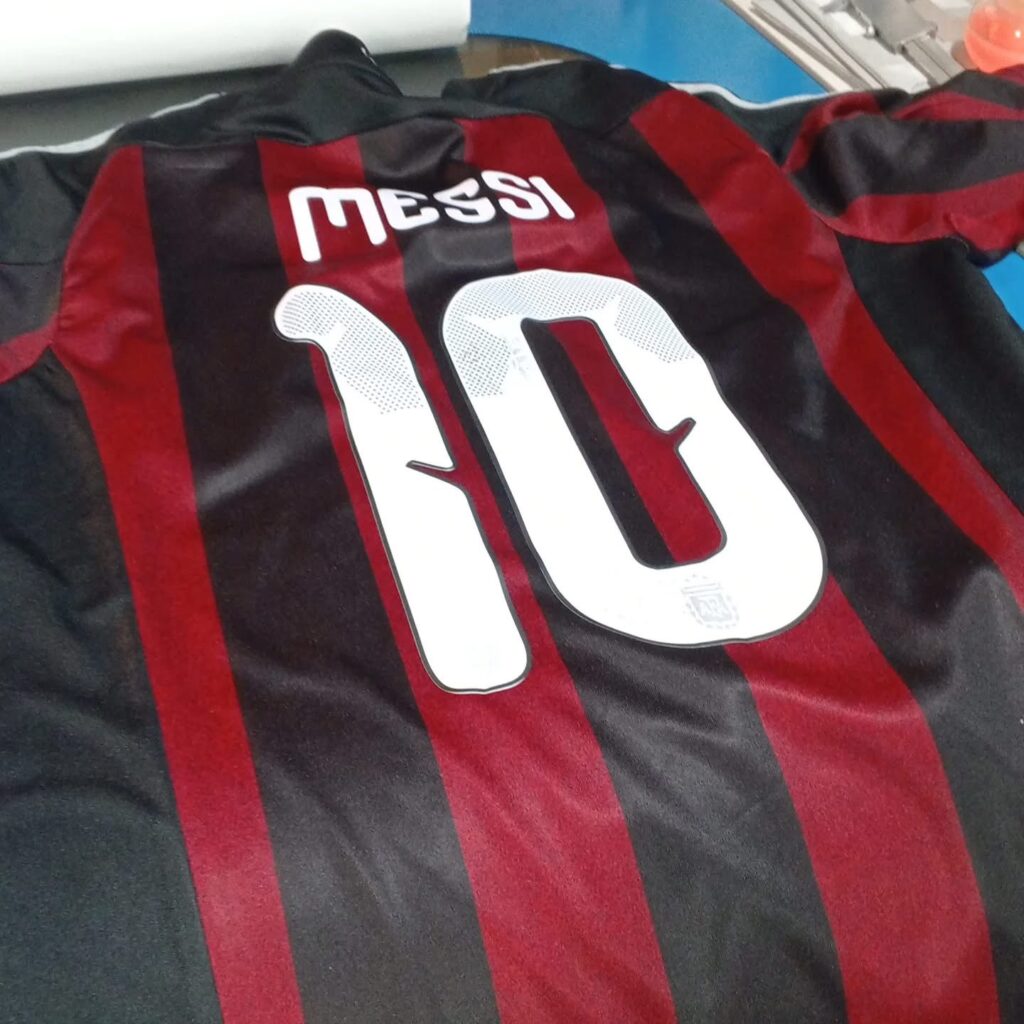 Red and black football shirt printed with Messi and the number 10.
