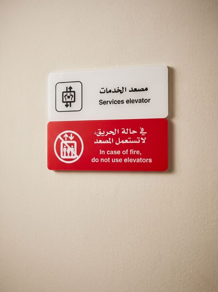 Angled view of bilingual elevator and fire-warning wall signs.