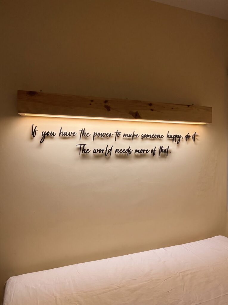 Illuminated plexiglass wall lettering installed beneath a wooden light frame by SHARK.