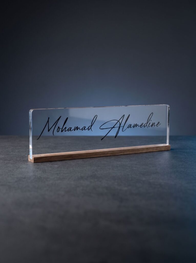 Clear desk nameplate with script lettering on a wooden base.